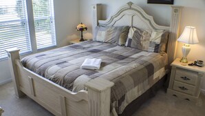 A neatly made bed with a quilt, a bedside lamp, and a nightstand with drawers. - Windsor Hills 2573 (Kissimmee)