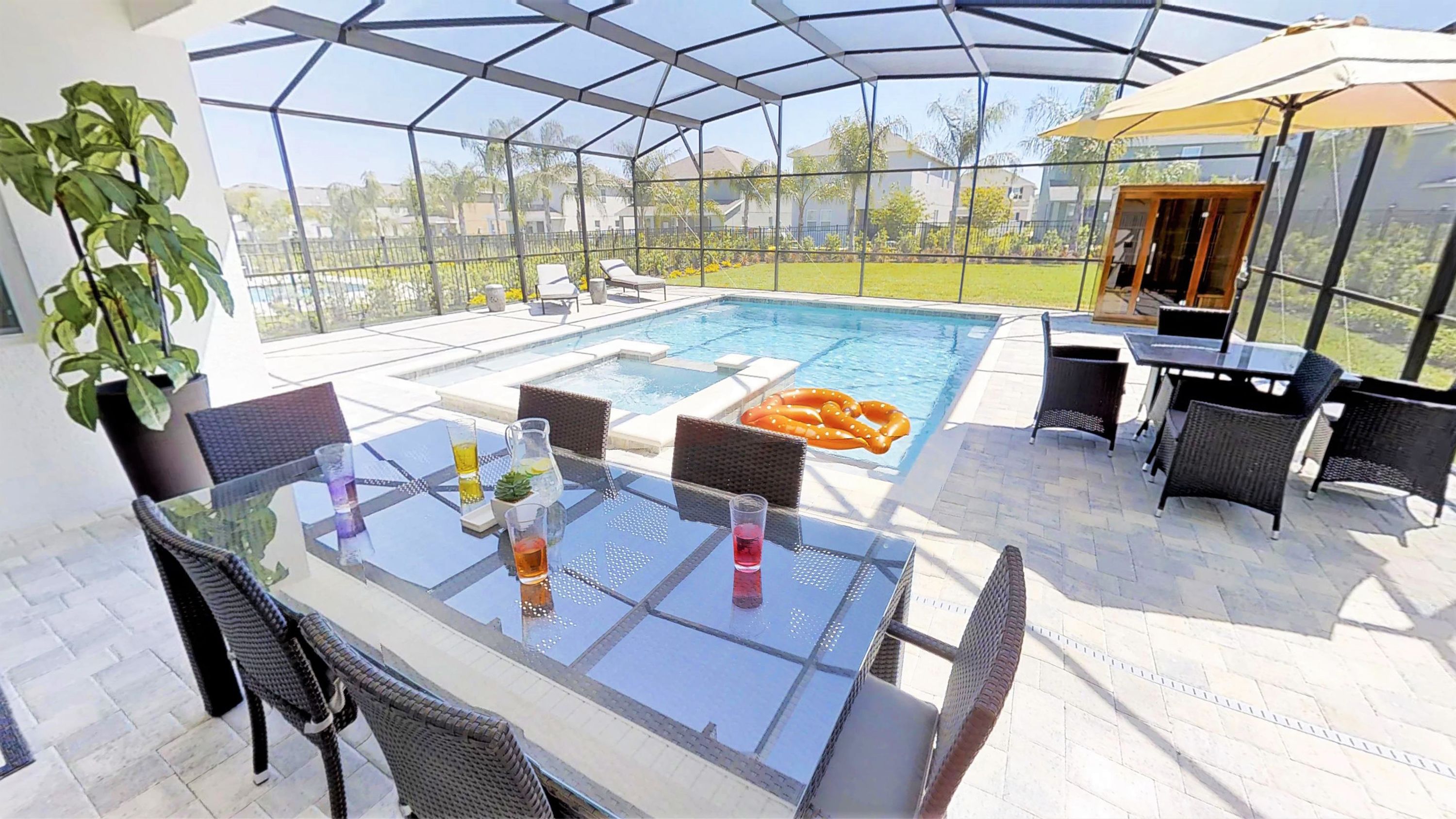 Un espacio al aire libre cubierto con piscina, mobiliario y una mesa con bebidas.