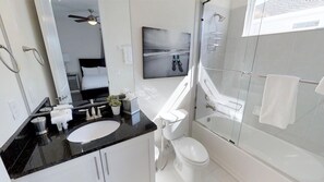 A modern bathroom with a black countertop sink, white toilet, and a glass-enclosed shower area. - Encore Resort at Reunion 7729 (Kissimmee)