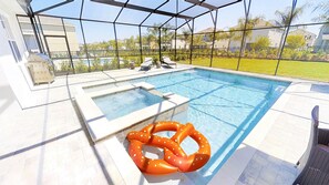 A swimming pool with a hot tub, lounge chairs, and a large orange inflatable ring. - Encore Resort at Reunion 7729 (Kissimmee)