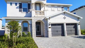 A two-story house with a stone facade, a balcony, and a garage. - Encore Resort at Reunion 7729 (Kissimmee)
