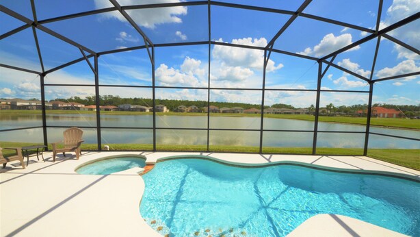 A swimming pool with a view of a lake and houses in the background. - Crystal Cove 4718 (Kissimmee)