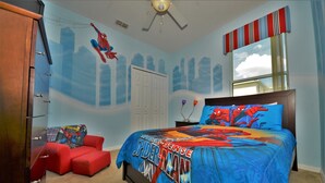 A bedroom with a bed, a red chair, a wardrobe, and a ceiling fan. - Crystal Cove 4718 (Kissimmee)