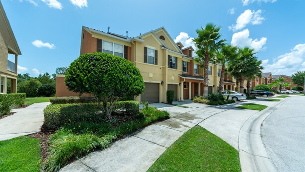 Una calle residencial con casas modernas de dos pisos, céspedes cuidados y un cielo despejado.