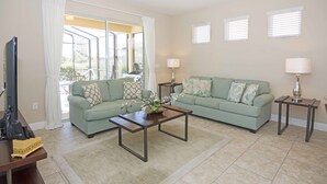 A living room with two green sofas, a coffee table, a TV, and two lamps. - Solterra 4405 (Davenport)