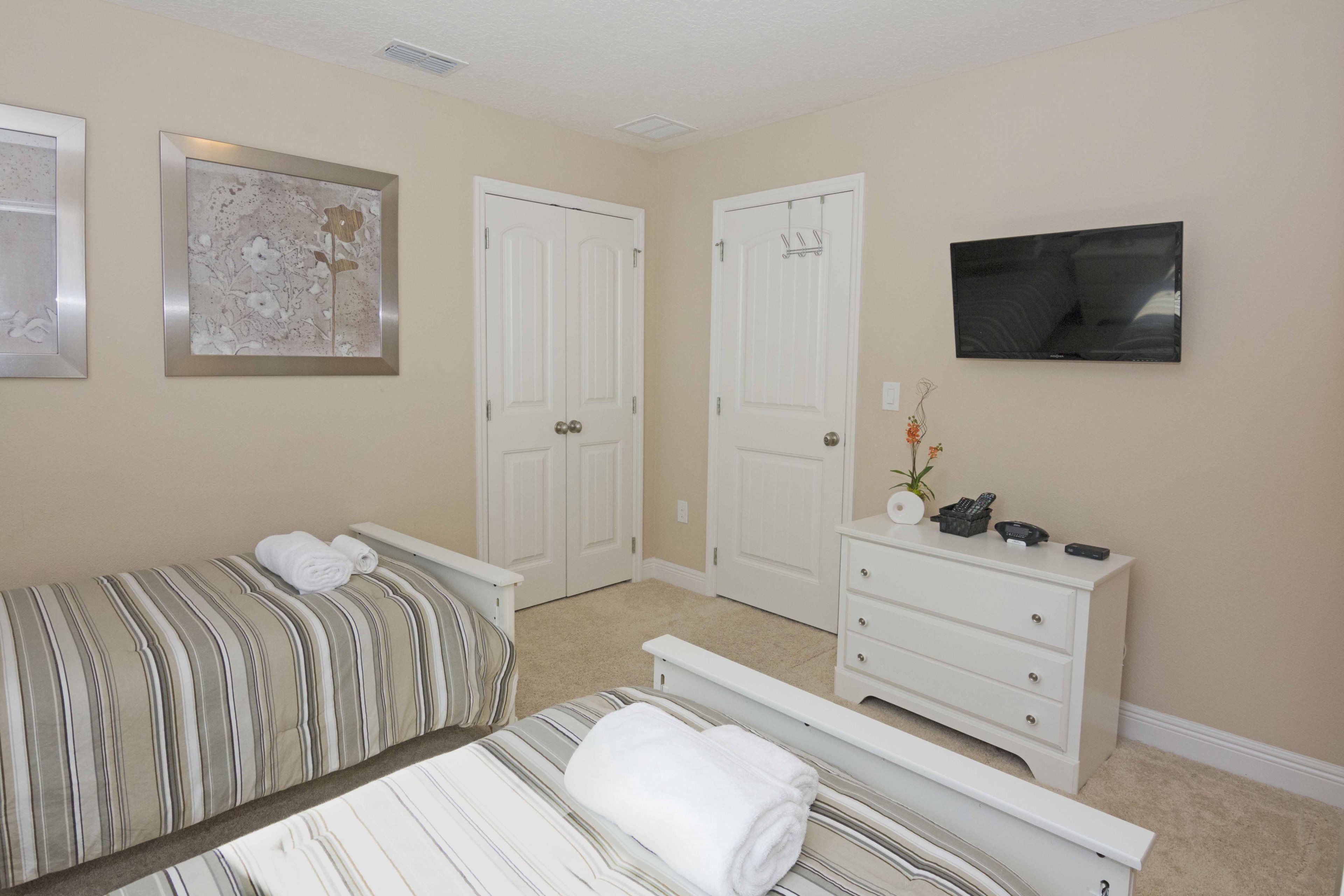A bedroom with a bed, a dresser, a television, and two doors.
