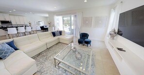 A modern living room with a white sofa, a glass coffee table, and a blue armchair. - Encore Resort at Reunion 7727 (Kissimmee)