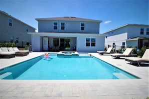 A swimming pool with lounge chairs and a house in the background. - Encore Resort at Reunion 7727 (Kissimmee)