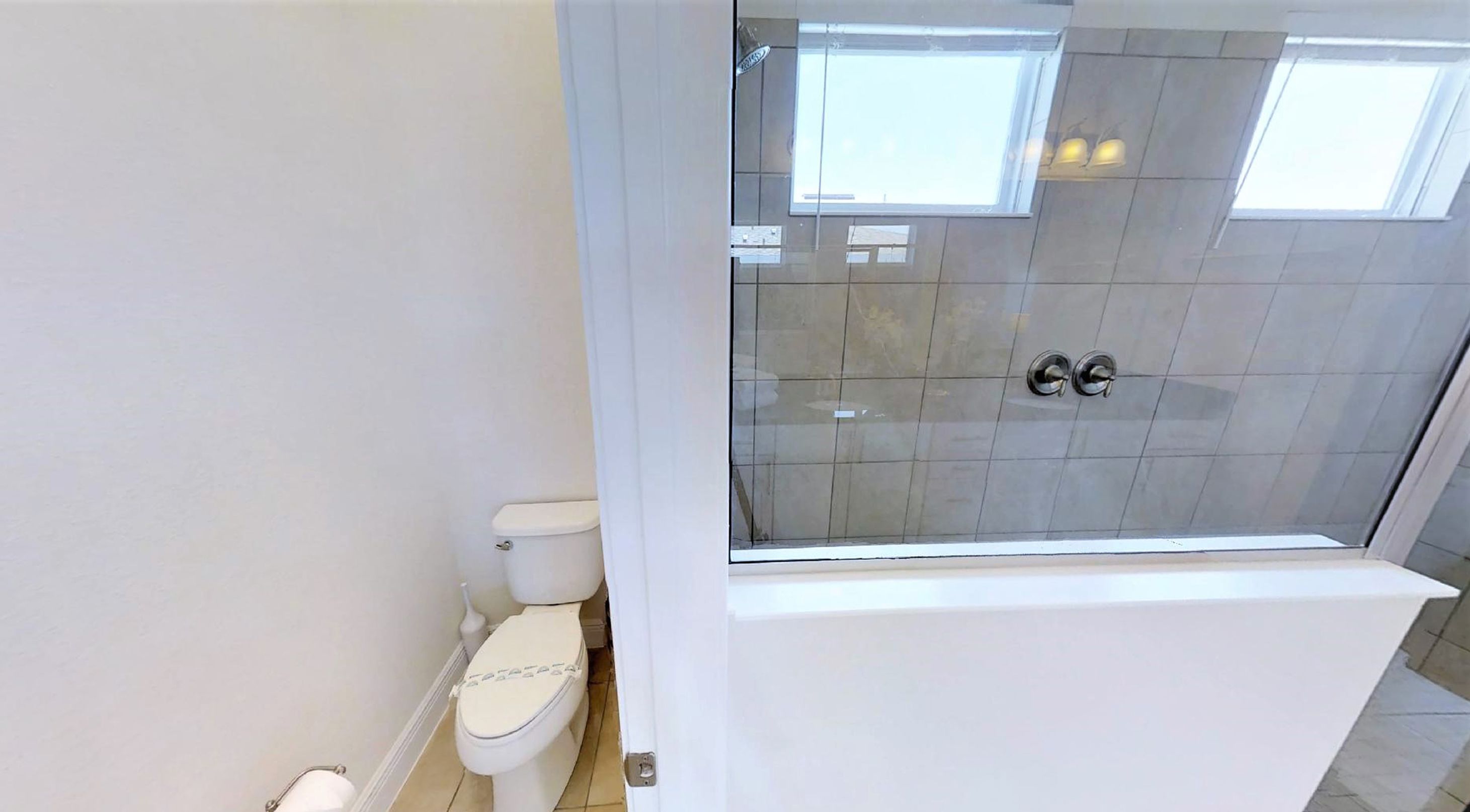 A bathroom with a toilet, a glass-enclosed shower, and a white bathtub.