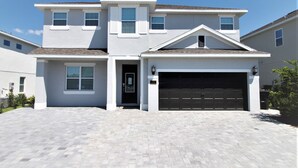Une maison à deux étages avec un garage, une porte d’entrée et une allée.