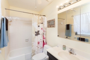 A bathroom with a bathtub, toilet, and a sink with a mirror above it.