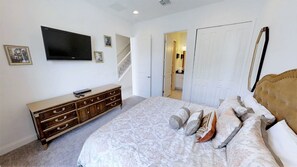 Quarto com cama, penteadeira, televisão e escada que leva a um banheiro.