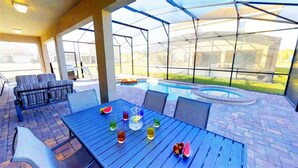 An outdoor patio with a pool, seating area, and a covered section. - Golden Palms Vacation Resort 24444 (Kissimmee)