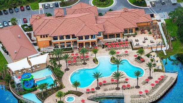 A resort with multiple swimming pools, a water slide, and a large building with a red-tiled roof.