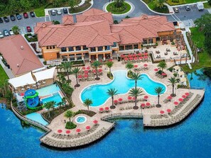 A resort with multiple swimming pools, a water slide, and a large building with a red-tiled roof. - Regal Oaks 2776 (Kissimmee)