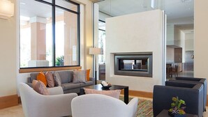 A modern living room with a sofa, armchairs, a coffee table, and a fireplace.