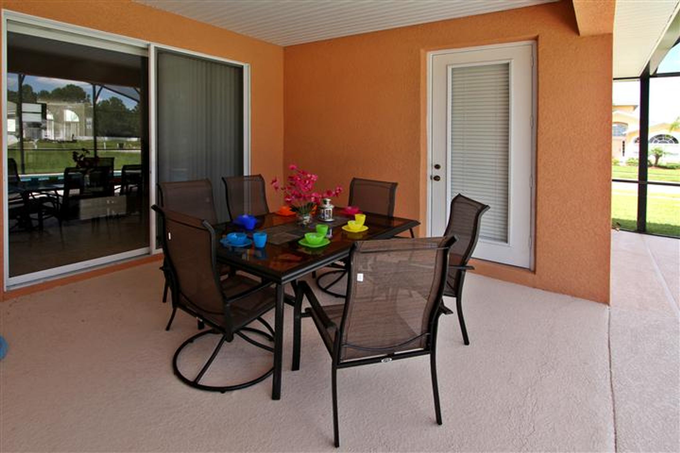 A covered patio with a table and chairs, a sliding glass door, and a view of the outdoors.
