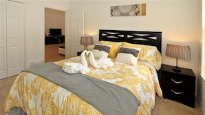 A neatly made bed with a floral bedspread, two bedside lamps, and a wall-mounted artwork. - Crystal Cove 4725 (Kissimmee)
