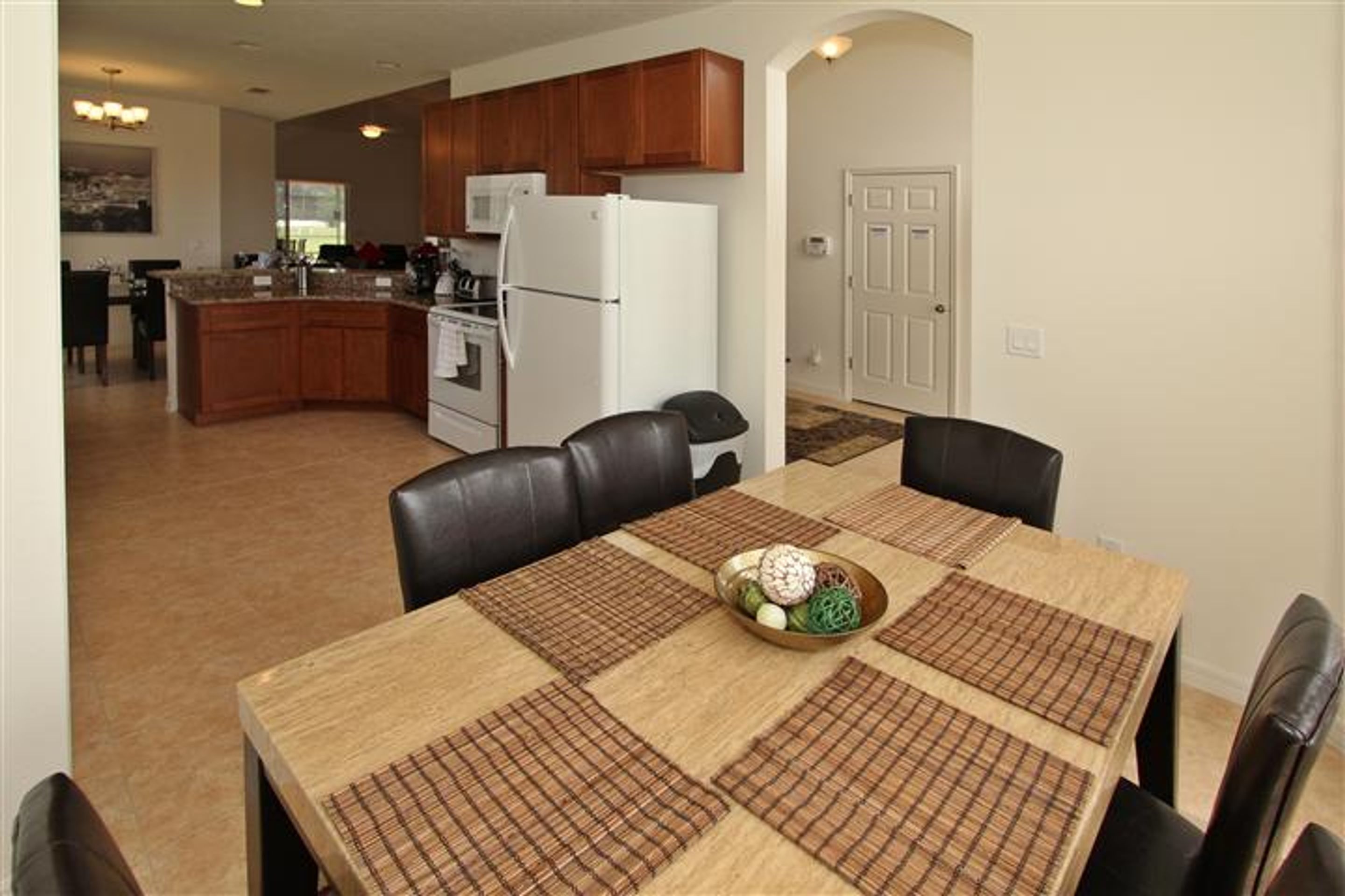 A dining area with a wooden table, black chairs, and a central decorative bowl.