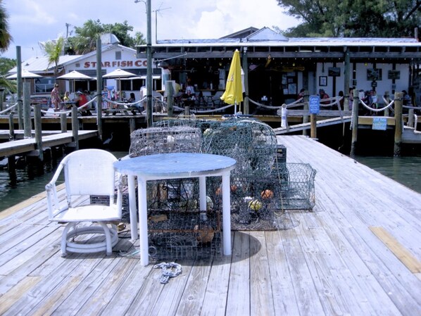 A wooden dock with a table and chairs, surrounded by lobster traps.