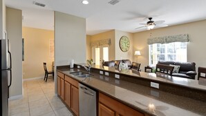 A kitchen with a dishwasher, a sink, and a countertop. There is a ceiling fan and a window with blinds. - Paradise Palms 8978 (Kissimmee)