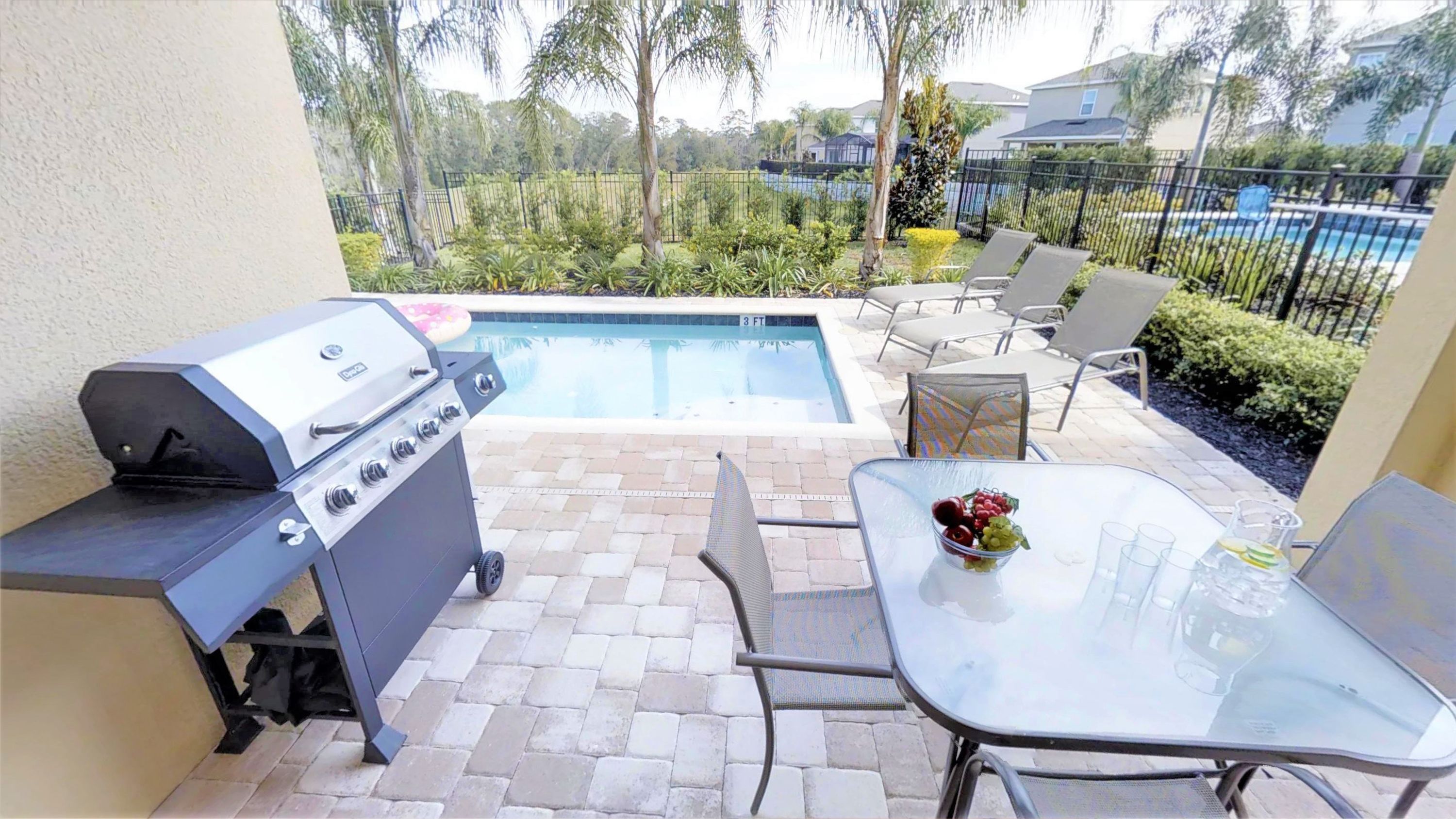 An outdoor patio with a grill, a pool, and seating.