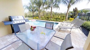 A poolside area with a grill, seating, and a table with fruit and drinks. - Encore Resort at Reunion 361 (Kissimmee)