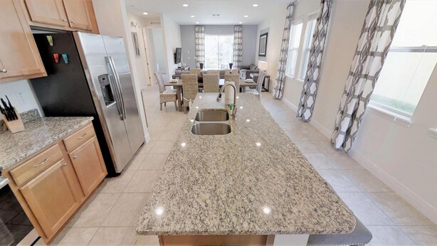 A modern kitchen with granite countertops, stainless steel appliances, and a central island with a sink. - Encore Resort at Reunion 361 (Kissimmee)