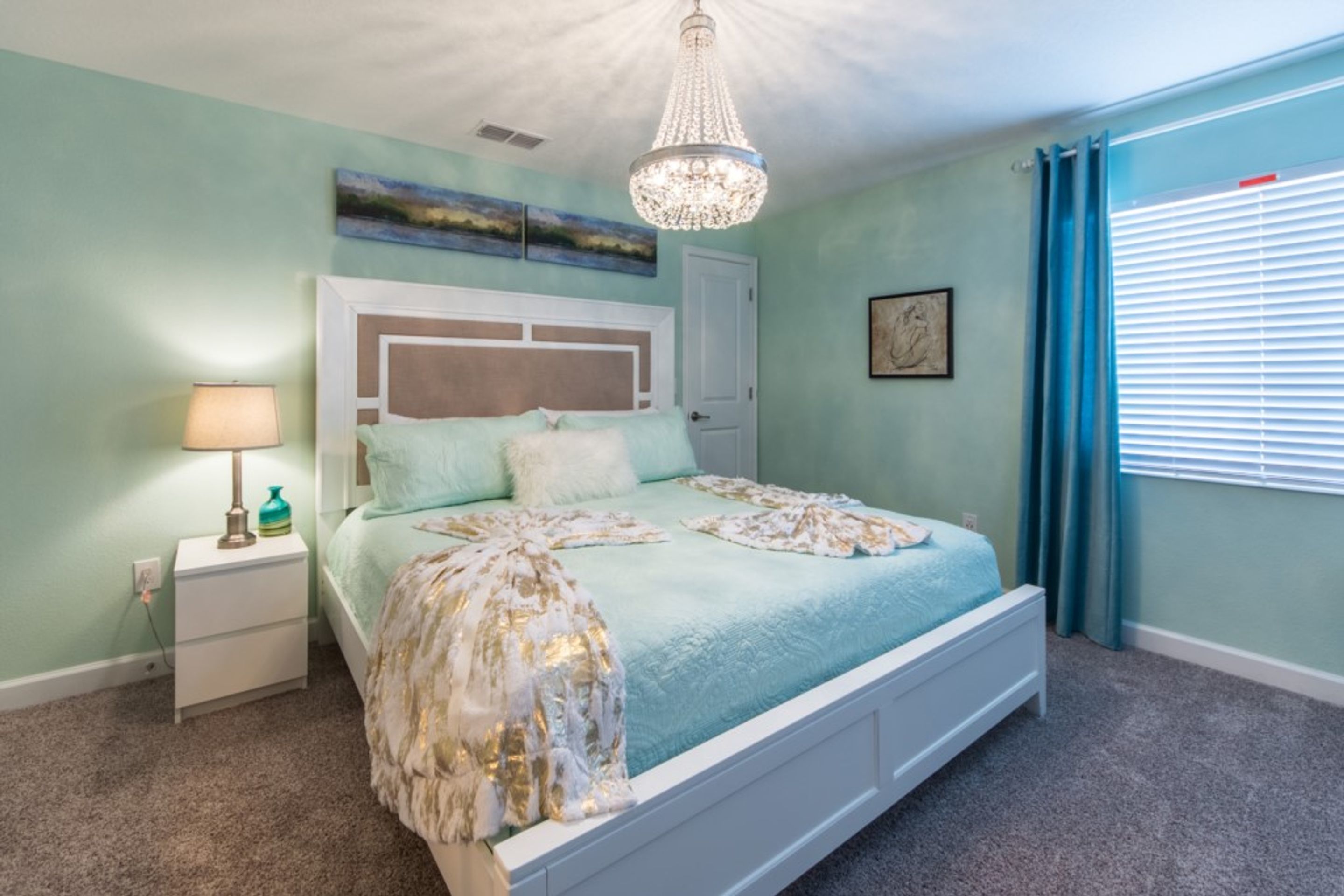 Ein Schlafzimmer mit Bett, Nachttisch, Lampe und einem Kunstwerk an der Wand.