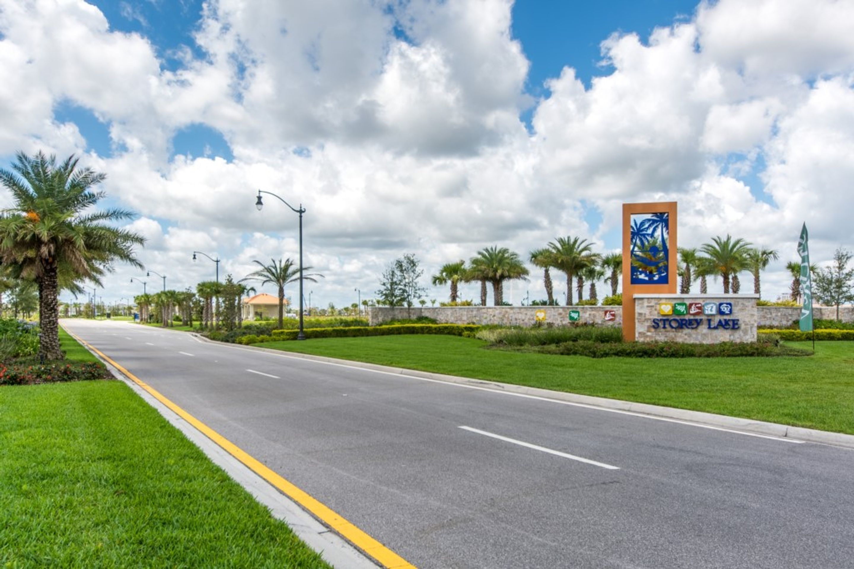 A road leading to a sign with 'Storey Lake' and various flags.