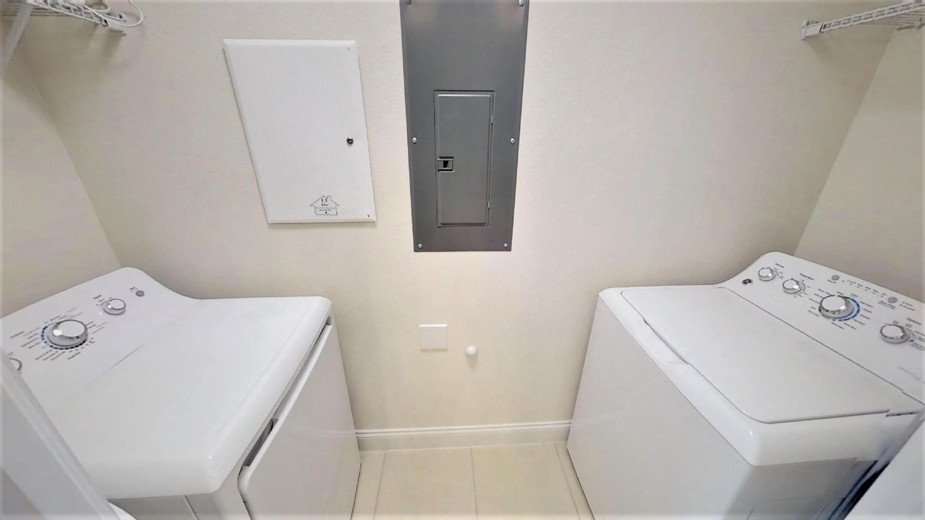 A laundry room with two washing machines and a utility meter.