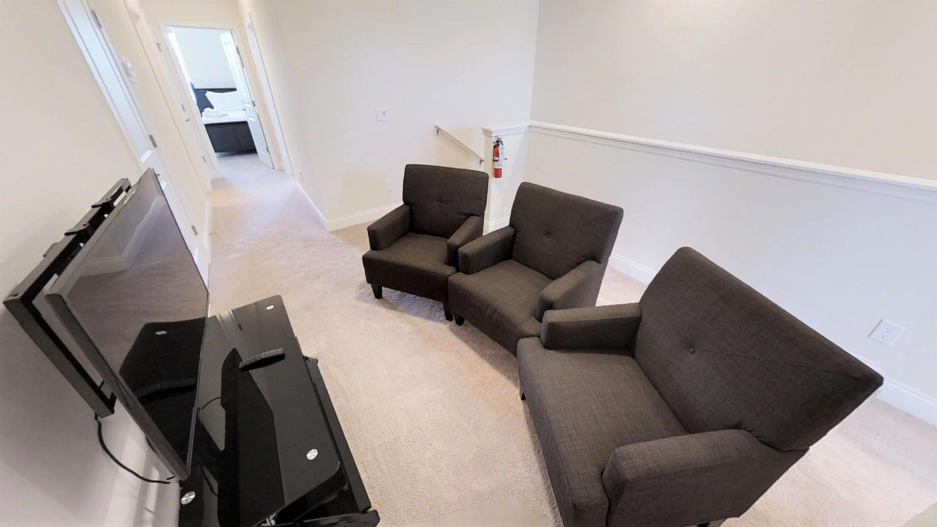Een woonkamer met een flatscreen televisie, twee fauteuils en een bank.