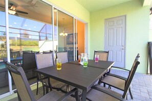 An outdoor patio with a table and chairs, a sliding glass door, and a door to the right.