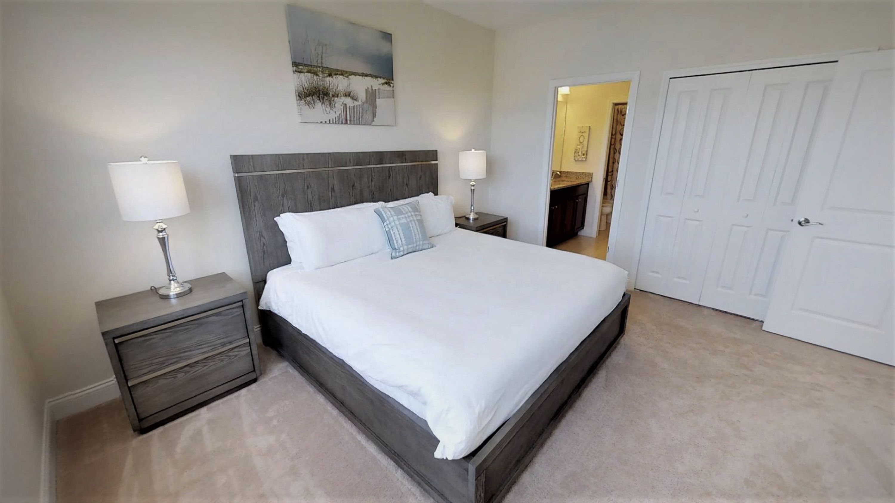 A bedroom with a large bed, two bedside tables with lamps, a headboard, and a door.