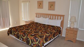 A bedroom with a large bed, two bedside tables, and a window with blinds. - Regal Palms Resort & Spa 2000 (Davenport)