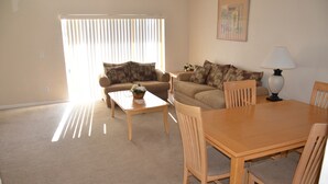 A living room with a sofa, a coffee table, and a dining table with chairs. - Regal Palms Resort & Spa 2000 (Davenport)