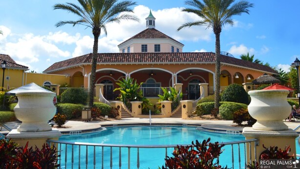 A pool area with a building in the background, palm trees, and a clear sky. - Regal Palms Resort & Spa 2000 (Davenport)