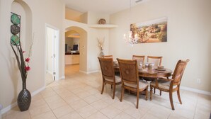 A dining area with a round wooden table, six chairs, and a chandelier. - Sand Hill 2620 (Davenport)