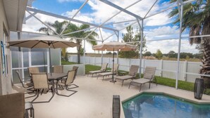 A covered outdoor area with a pool, lounge chairs, and umbrellas. - Sand Hill 2620 (Davenport)