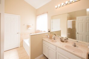 A bathroom with a bathtub, a vanity with a mirror, and a window with curtains.