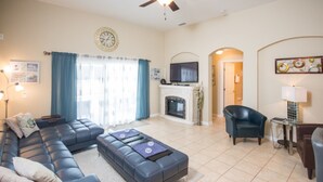 A living room with a sectional sofa, a fireplace, a television, and a ceiling fan. - Sand Hill 2620 (Davenport)