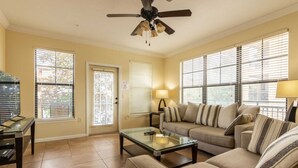A living room with a sofa, coffee table, and ceiling fan. - Bella Piazza 903 - 827 (Davenport)