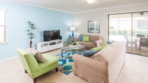 A living room with a television, sofa, armchair, and a coffee table. - Windsor at Westside 2145 (Kissimmee)