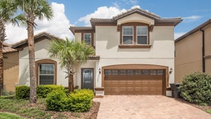 A two-story house with a brown garage door, a front entrance, and a landscaped driveway. - Windsor at Westside 2145 (Kissimmee)