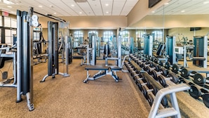A gym with various exercise equipment, mirrors, and windows. - Windsor at Westside 2145 (Kissimmee)