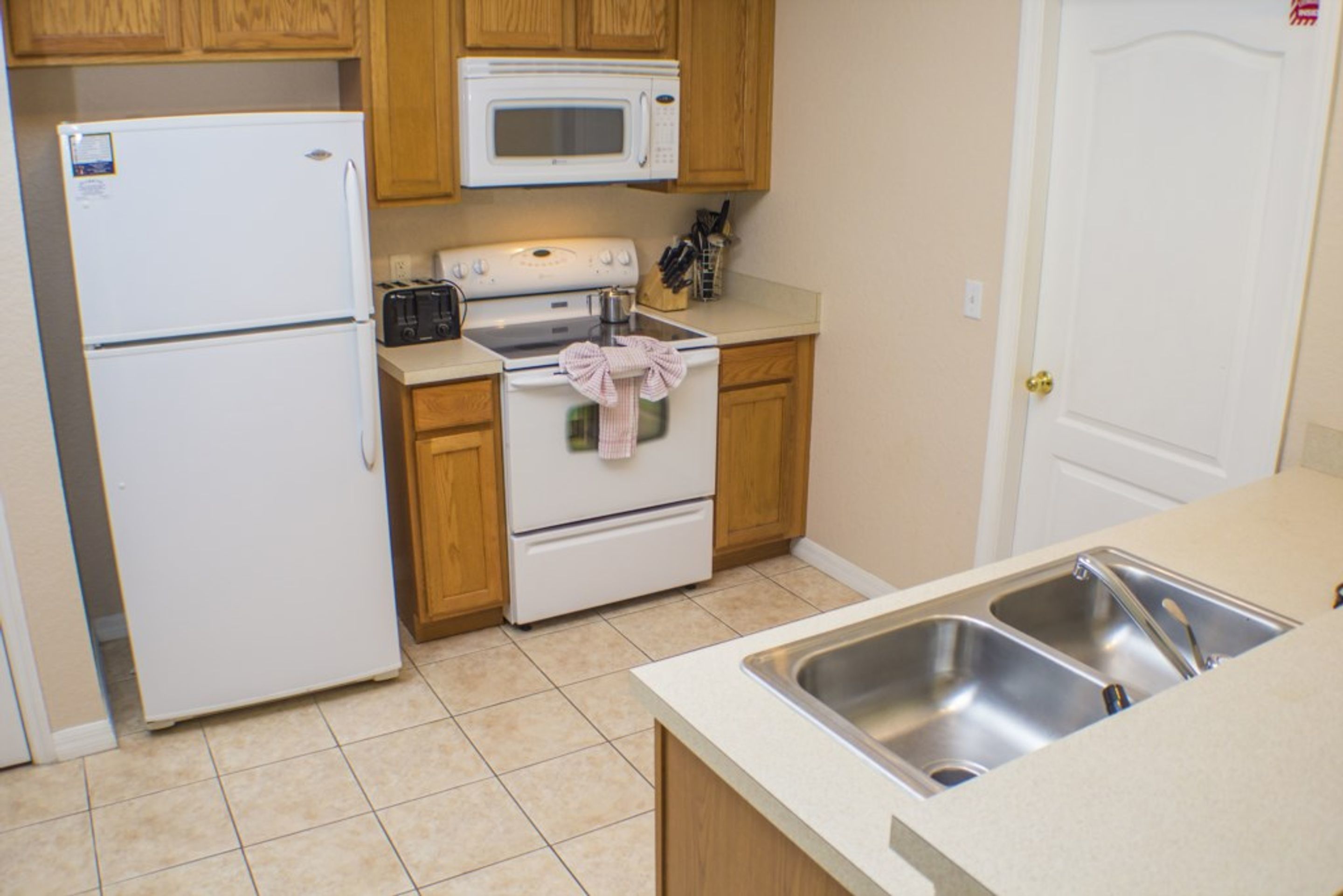 Una cocina equipada con refrigerador, microondas, estufa y pileta.