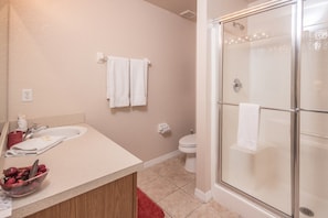 A bathroom with a glass-enclosed shower, a sink with a mirror, and a toilet.