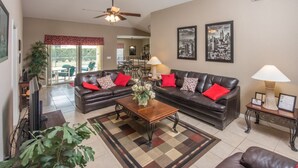 A living room with two leather sofas, a coffee table, and a television. There are two lamps on side tables, and a ceiling fan above the sofas. - Silver Creek 1435 (Clermont)