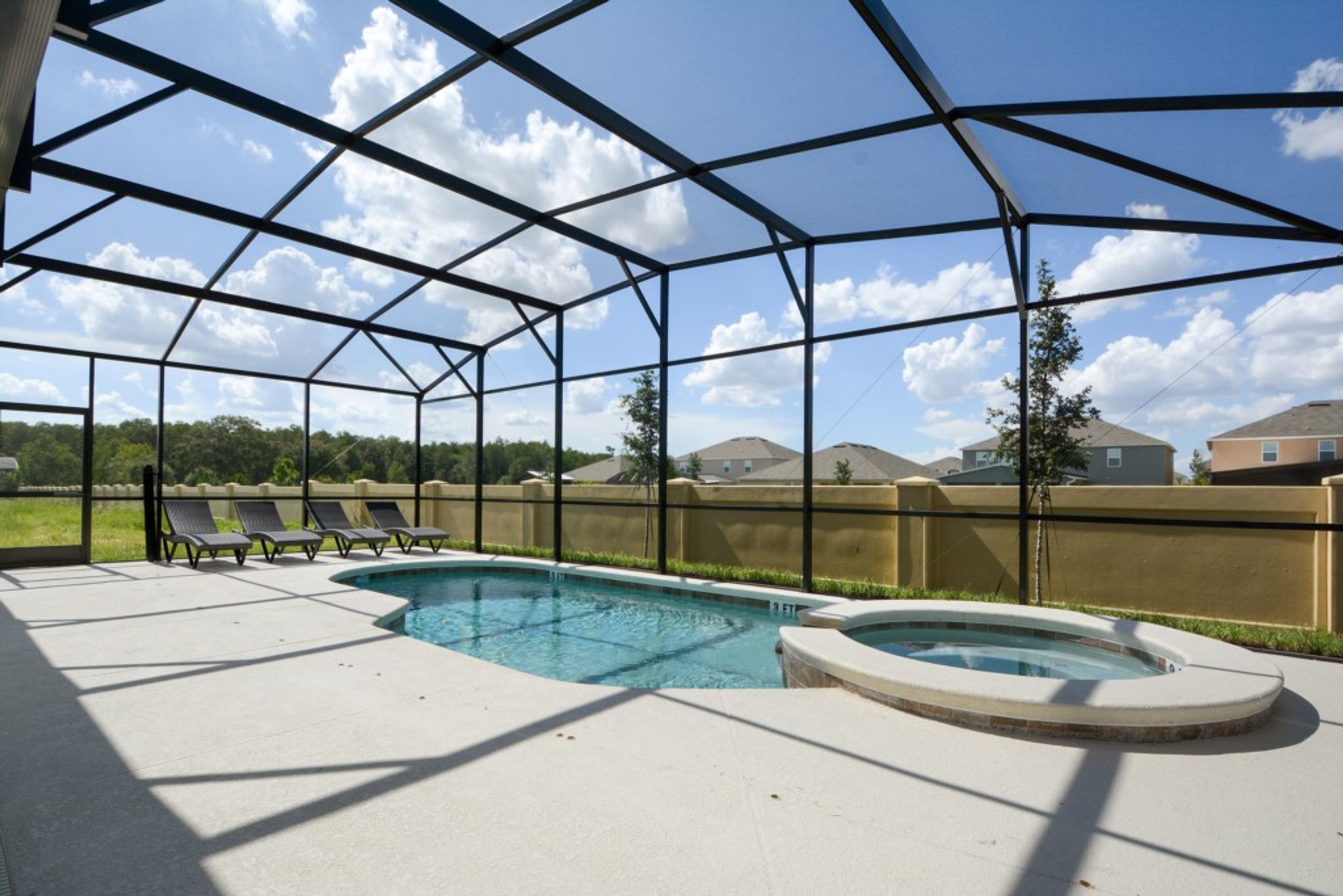 Una piscina exterior cubierta con sillones reclinables y un jacuzzi.