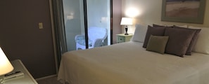 Ein Hotelzimmer mit einem Bett, einem Nachttisch mit Lampe, einem Sessel und einem Fenster mit Blick.